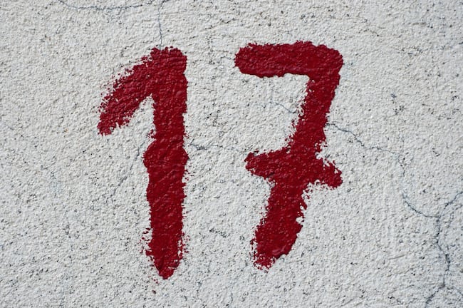 Close-up of a small number 17 painted in red on a section from the stone walls surrounding the Parliament Palace in Bucharest.