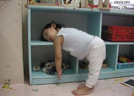 Fotografia de um bebe dormindo em pé com o corpo dobrado