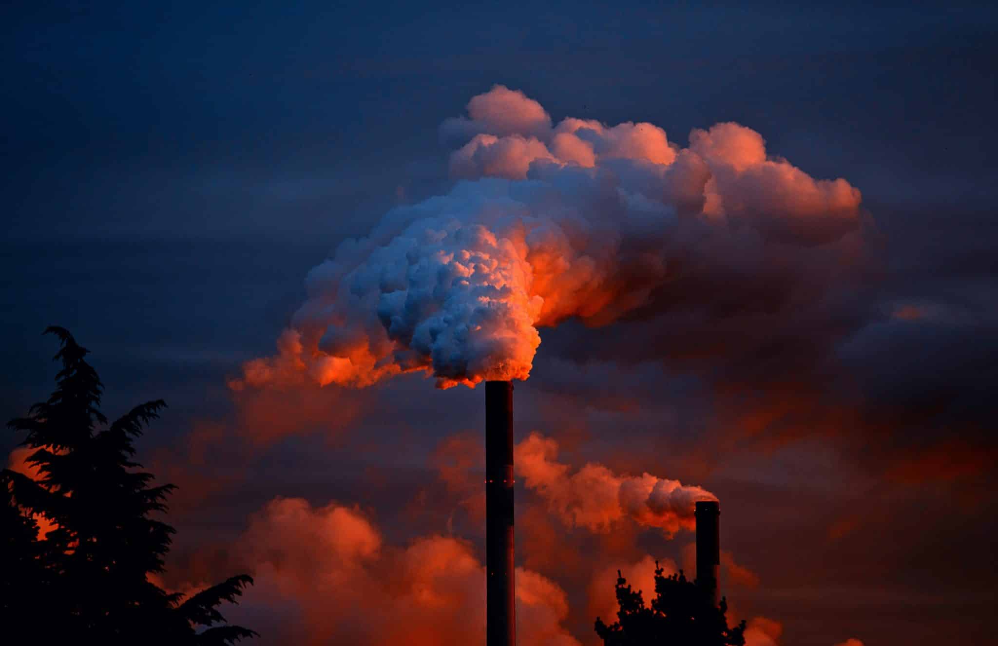 Fotografia de chaminés industriais emitindo gases poluentes